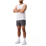 A man in a white sleeveless shirt, Canterbury Everest Woven Shorts, white socks, and white sneakers stands with arms crossed against a plain white background.