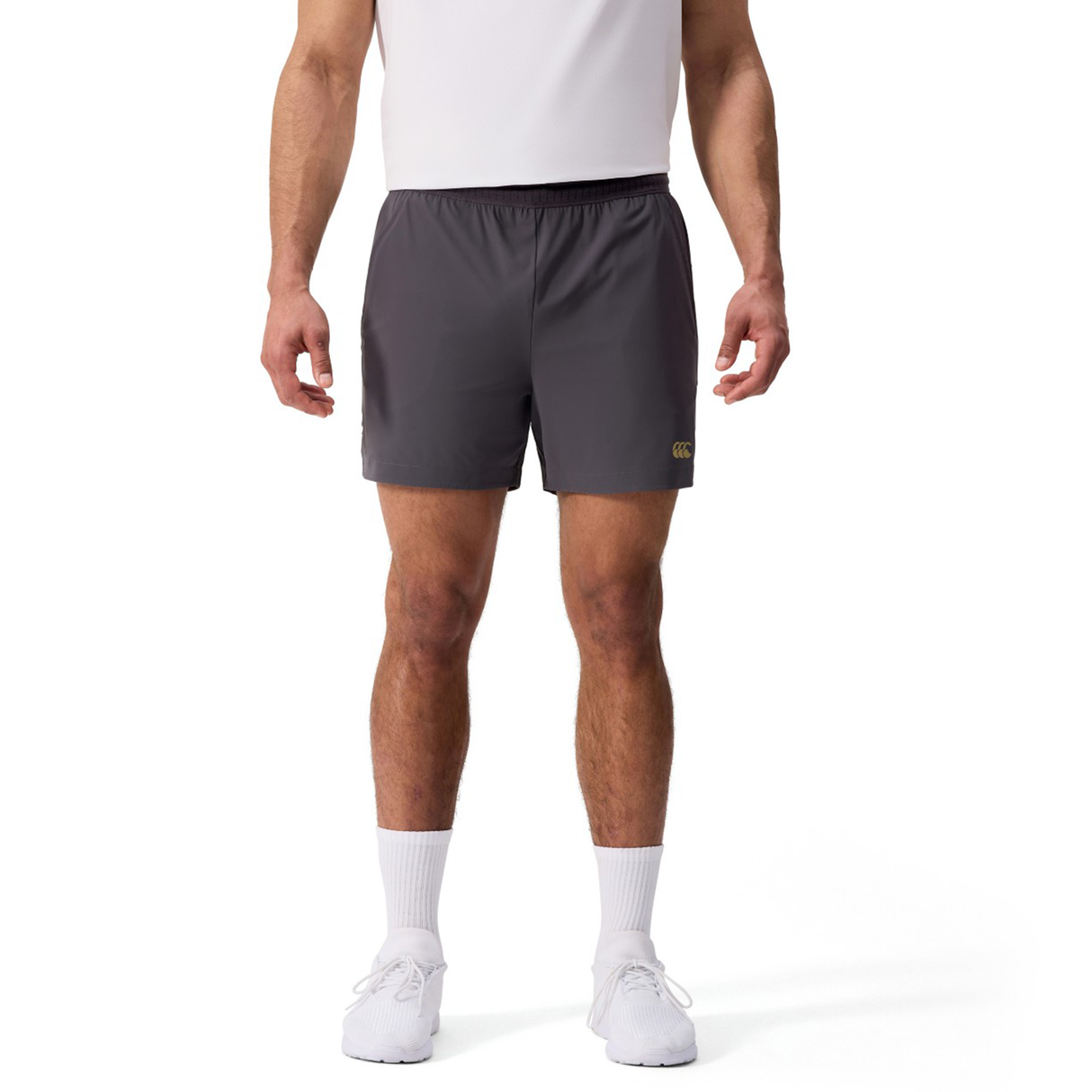 A person in a white t-shirt, Canterbury Everest Woven Shorts, white socks, and white sneakers stands against a plain white background.