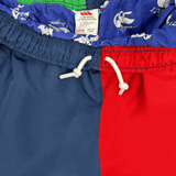 Close-up of a Canterbury Youth Harlequin Stadium Trackpant 24 with red, blue, and green panels featuring a white drawstring. The label reads "Canterbury," size "14YRS," echoing the vibrant design of the Harlequin Trackpant.