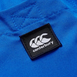 Close-up of the black Canterbury logo patch sewn onto bright blue fabric with visible stitching, featured on the Canterbury Uglies Tactic Short.