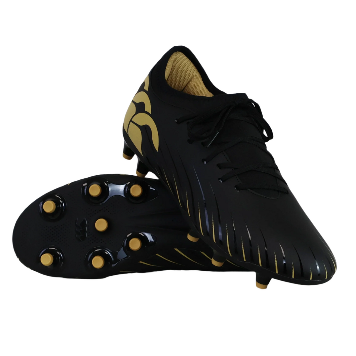 The Canterbury Phoenix 2.0 Team FG rugby boots by Canterbury, in black with gold accents and studs, are shown with one upright and one on its side—ideal as firm ground rugby boots.