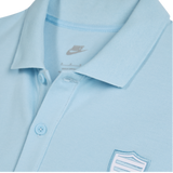 Close-up of the Nike Racing 92 25/26 Pique Polo in light blue, crafted from breathable cotton with buttons and a shield-shaped embroidered chest patch.