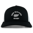 The Nations of Rugby New Zealand Retro Trucker Cap by EMB S&S Activewear features a black and white design, "New Zealand Rugby" text, silver fern logo on the front, and a classic snapback closure for adjustable fit.
