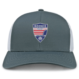 A gray and white Cincinnati Rookie Rugby Retro Trucker Cap from EMB Alpha Broder with a "Rookie Rugby Cincinnati" patch featuring stars, stripes, and a rugby ball design. The snapback closure ensures a comfortable fit, while the embroidered design adds a touch of vintage flair.