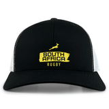 The EMB S&S Activewear Nations of Rugby South Africa Brush Stroke Retro Trucker Cap features a black and white design with "South Africa Rugby" in yellow, a springbok graphic, and an adjustable snapback closure.