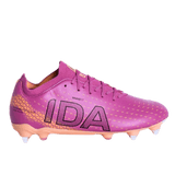 The IDA Sports IDA Helia Club SG - Dark Pink is a women's soft ground soccer cleat in pink with orange accents, black geometric patterns, "IDA" on the side, and four sole studs.