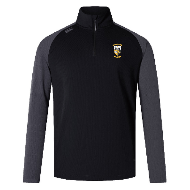 The Spokane Rugby Women's Elite First Layer by Canterbury, in black and gray, is a long-sleeve quarter-zip pullover from EMB Canterbury. It showcases an Elite First Layer design with a logo on the chest and is crafted with VapoDri technology. Its honeycomb fabric ensures optimal comfort and breathability.