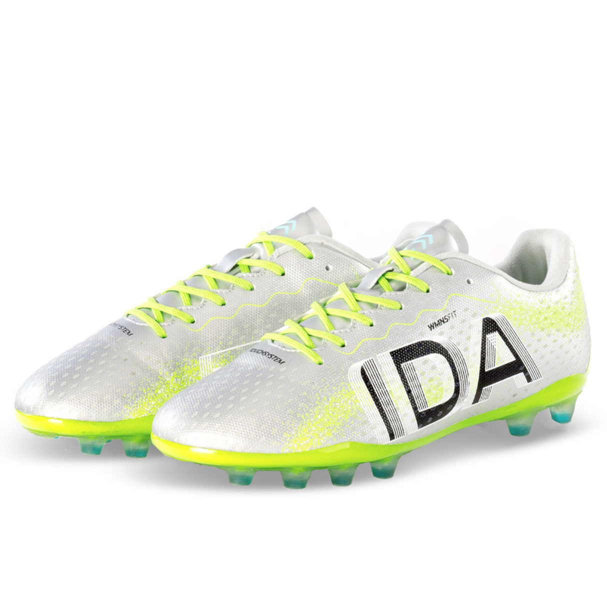 The silver "Ida Women's Rise Club FG 'Play All Day'" cleats by IDA Sports feature black text, neon green details, and cleats. Made from vegan leather, they ensure an adjustable fit and are elegantly displayed side by side on a plain background.