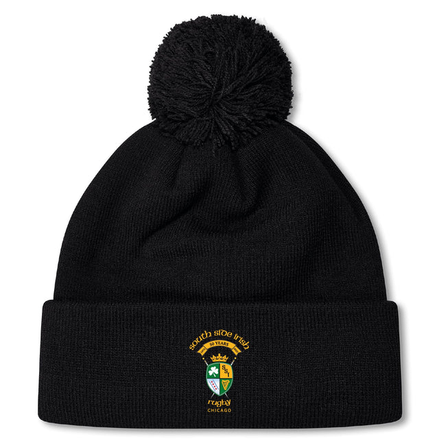 The South Side Irish 50th Anniversary Pom Pom Beanie by EMB Canterbury features a black knit, fleece lining for warmth, a large pom-pom, and an embroidered South Side Irish Rugby Chicago crest on the front cuff.