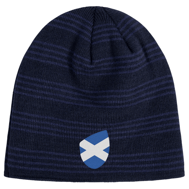 The EMB Canterbury Scotland Shield Beanie is a navy blue knit hat featuring horizontal stripes and a small blue and white shield emblem with the Scottish flag.