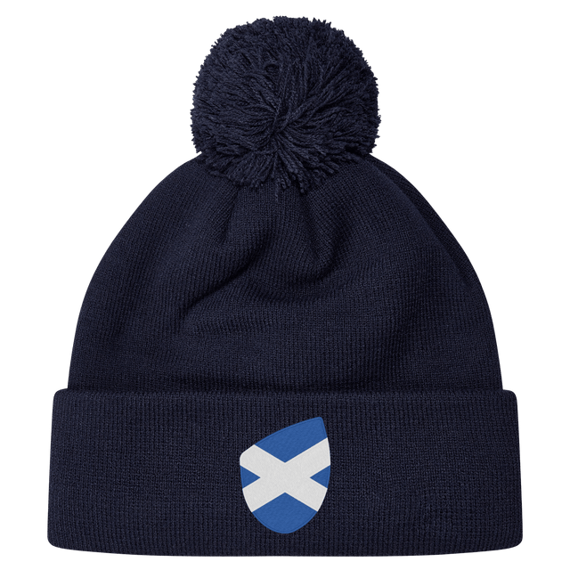The Scotland Shield Pom Pom Beanie by EMB Canterbury, in navy blue, features a Scottish flag emblem on the front, offering warmth and national pride.