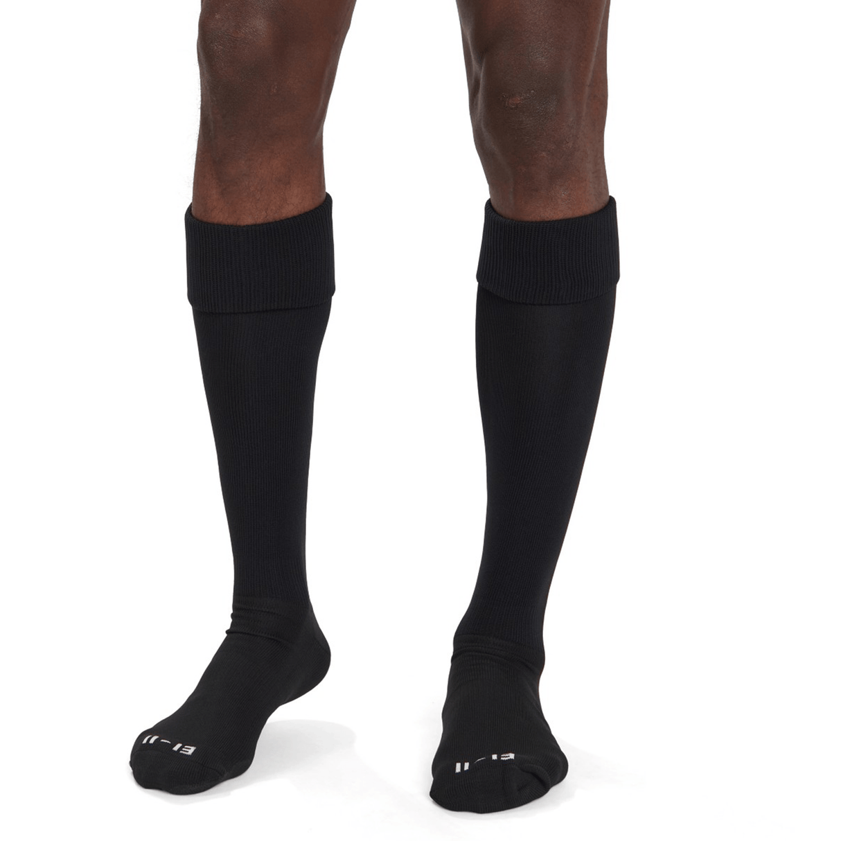 A person wearing Canterbury Playing Socks stands on a white background. The long, black, knee-high socks feature a folded top with the word "LEFT" visible on the left sock. These socks by Canterbury offer a cushioned foot bed for extra comfort.