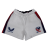 Women's USA Rugby Pro Home Shorts by Castore feature a moisture-wicking fabric, an elasticated waistband, and are adorned with the "CASTORE" logo on the left and "USA RUGBY" emblem on the right. Stylish red and blue stripes run down the sides.