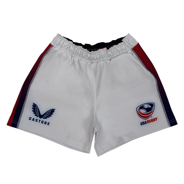 The USA Rugby Pro Home Short by Castore has a logo on the left, elasticated waistband, red and blue side accents, and is made from moisture-wicking fabric for comfort and performance on the field.