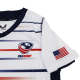 The Castore Women's USA Rugby Replica Home Jersey 22/23 features horizontal red, white, and blue stripes, the USA Rugby chest logo, and an American flag patch on the sleeve—ideal for fans seeking an authentic women's rugby jersey.