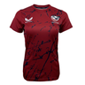 The maroon Women's USA Rugby Printed Training Tee by Castore features a navy blue splatter design, with the "Castore" logo on the left and the "USA Rugby" emblem on the right, offering style and functionality for any USA Rugby fan.
