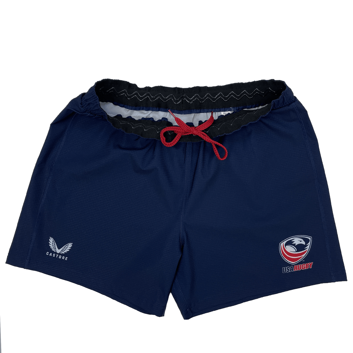 The Women's USA Rugby RWC Pro Away Shorts by Castore are navy blue with a red drawstring, featuring USA Rugby and Castore logos. They include a silicone waist grip for a better fit and come with a handy mouth guard pocket.
