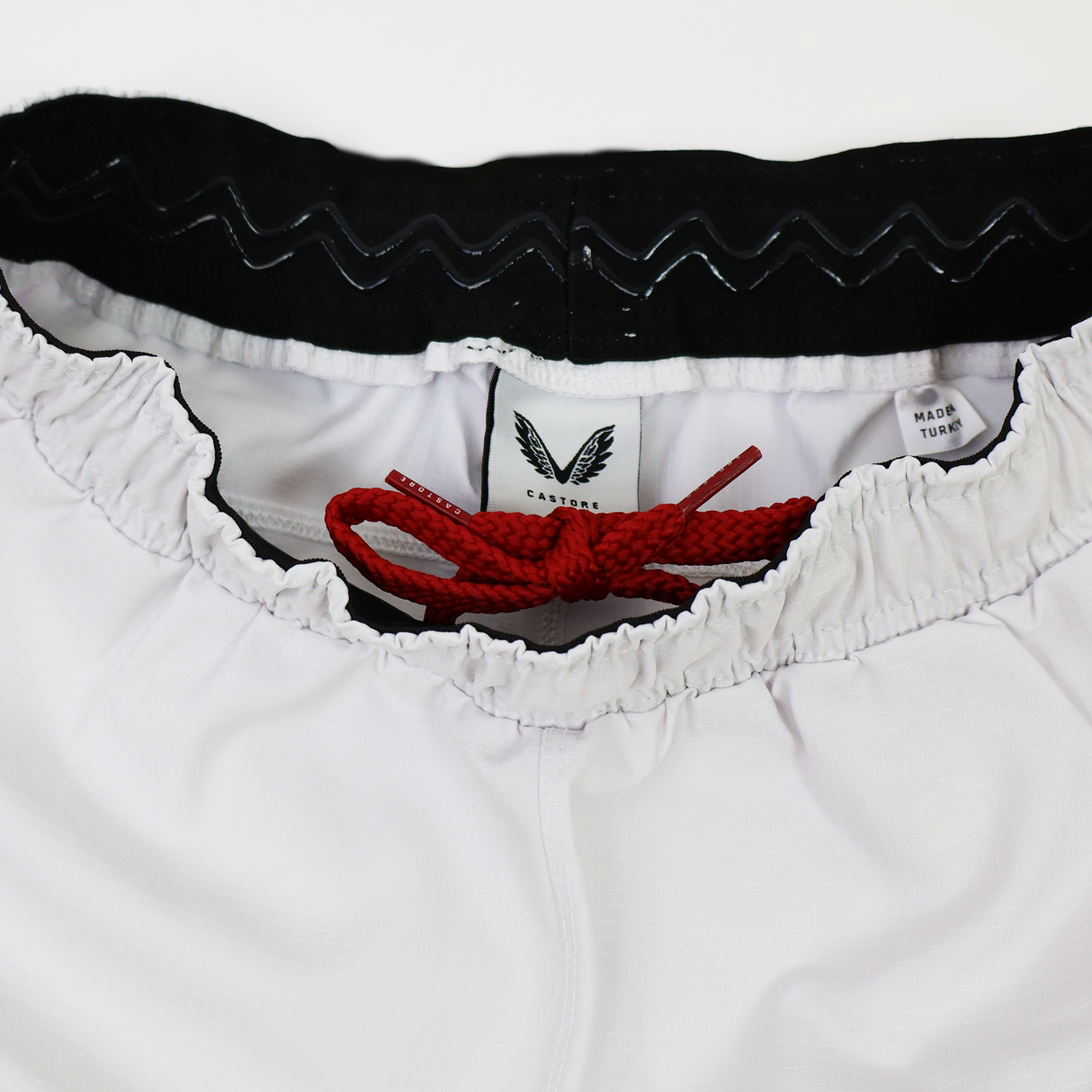 Close-up of the waistband on the Castore Women's USA Rugby 22/23 RWC Home Pro Short, showing a black inner band, red drawstring, and manufacturer tag.