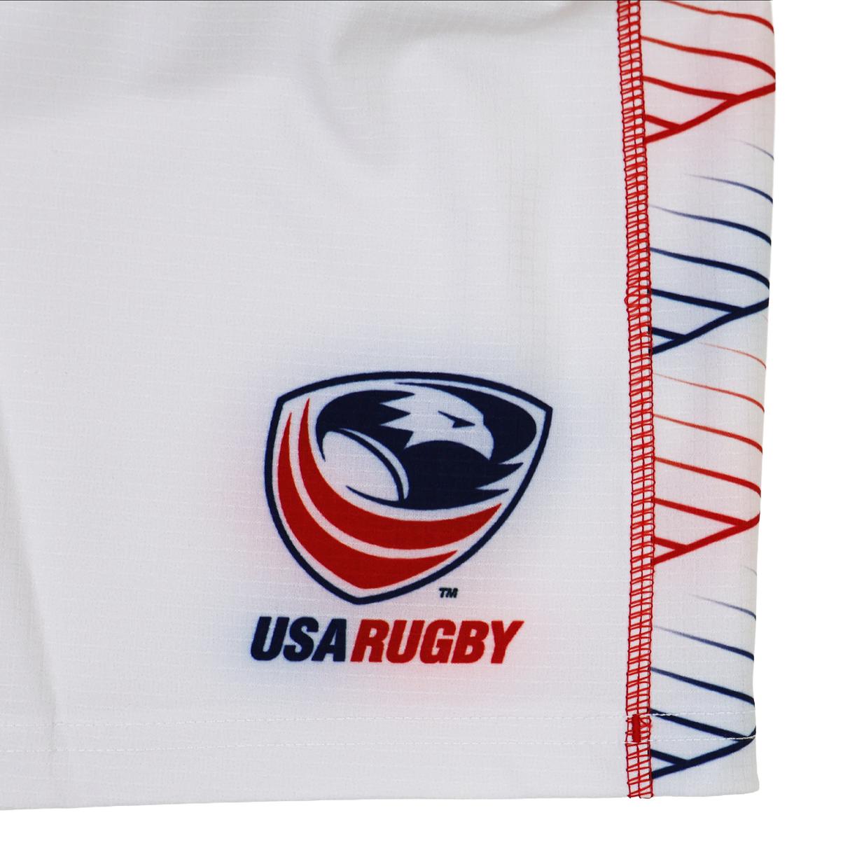 The Women's USA Rugby 22/23 RWC Home Pro Short by Castore features a white base, the USA Rugby eagle head logo with red, white, and blue accents, plus a geometric red and blue line pattern on the side.