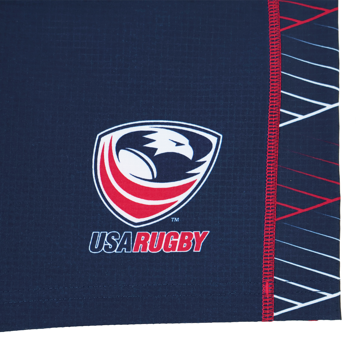Close-up of the USA Rugby eagle and shield logo with "USA RUGBY" text on a dark blue Castore fabric with red and white accents, featured on the Women's USA Rugby 22/23 7s RWC Away Pro Short by Castore.