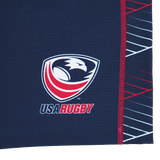 Close-up of the USA Rugby eagle and shield logo with "USA RUGBY" text on a dark blue Castore fabric with red and white accents, featured on the Women's USA Rugby 22/23 7s RWC Away Pro Short by Castore.