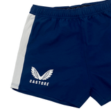The Women's USA Rugby Pro Home Shorts by Castore are blue with a white side stripe, feature moisture-wicking fabric, and have the iconic Castore wings logo on the left leg. They're perfect for rugby enthusiasts and stylish enough for any occasion.