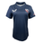 The Women's USA Rugby Training Jersey by Castore, in navy blue, features a "USA" logo, white bird emblem, and American flag on the sleeve. Made with moisture-wicking fabric for an athletic fit, it provides ultimate comfort and performance.