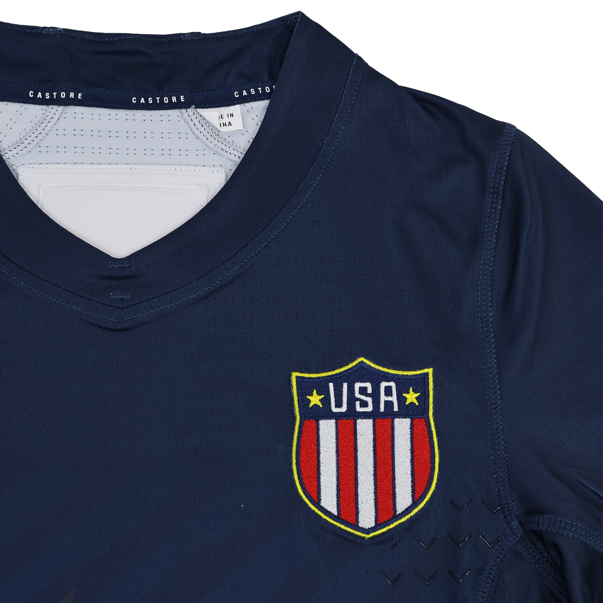 The Women's USA Rugby 24/25 7s Olympic Pro Home Jersey by Castore features a navy design with a USA crest displaying red and white stripes plus yellow trim on the chest.