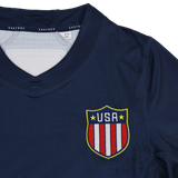 The Women's USA Rugby 24/25 7s Olympic Pro Home Jersey by Castore features a navy design with a USA crest displaying red and white stripes plus yellow trim on the chest.