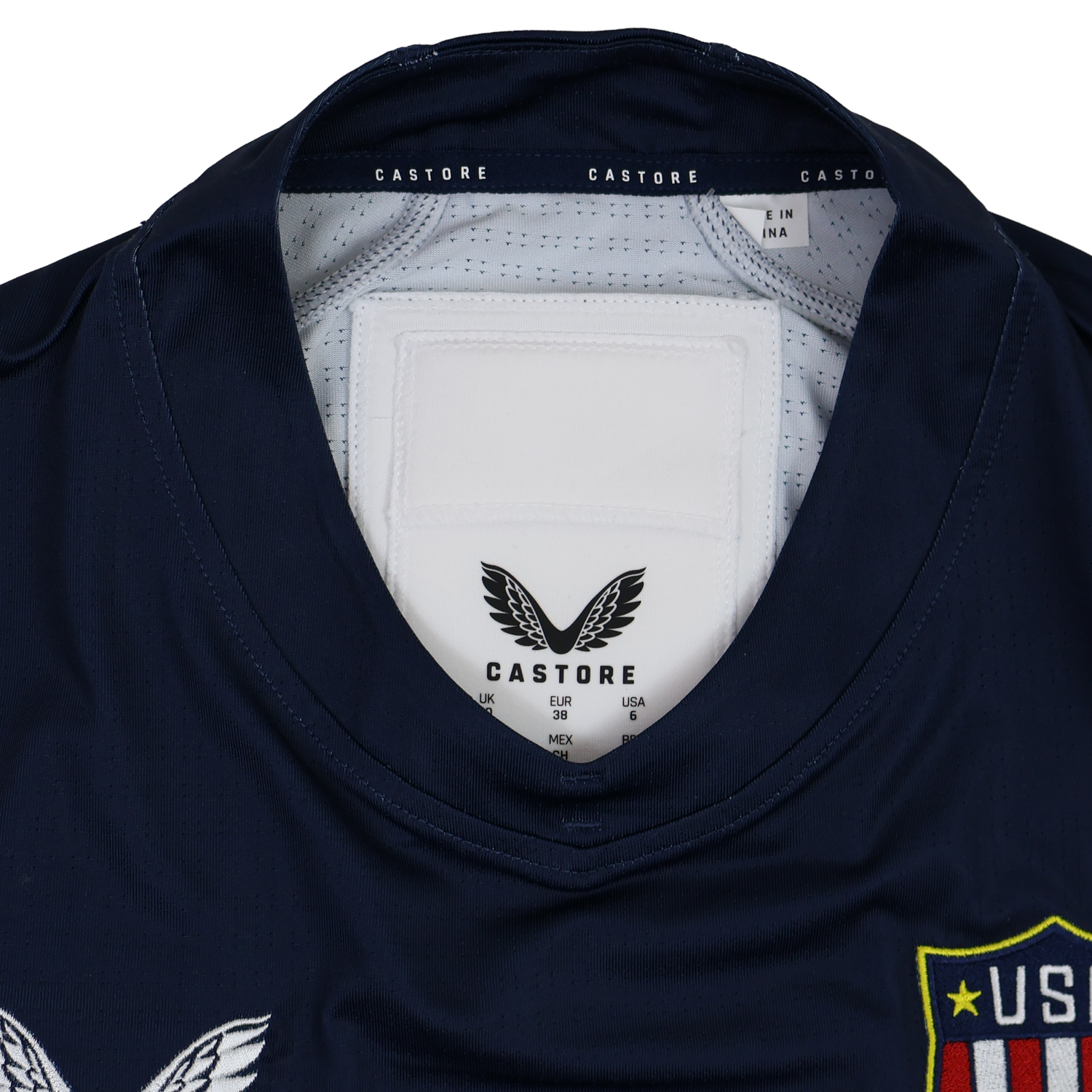 Close-up of the collar and label on the Women's USA Rugby 24/25 7s Olympic Pro Home Jersey by Castore, showing the brand logo, sizing details, and part of the team crest.