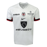 The Stade Toulousain Replica Away Jersey by Nike is a white jersey that showcases logos for Airbus, Rempart Mutuelle, and Peugeot. It features the iconic red and black emblem with intertwined letters.