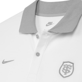 Close-up of the Stade Toulousain 25/26 Premium Pique Polo by Nike: a white collared rugby polo with gray buttons, gray collar, and two embroidered logos on the chest.