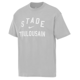 The Stade Toulousain 25/26 Premium Loose-Fit T-Shirt by Nike is a light grey cotton tee with "STADE TOULOUSAIN" and a white Nike logo printed on the front.