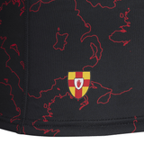 The Ulster Rugby 24/25 Replica Provincial Jersey by Castore flaunts a black fabric embellished with a bold red map pattern and features a unique crest, showcasing a red hand on a yellow and red shield. Designed by Castore, it perfectly blends tradition with modern styling for fans.