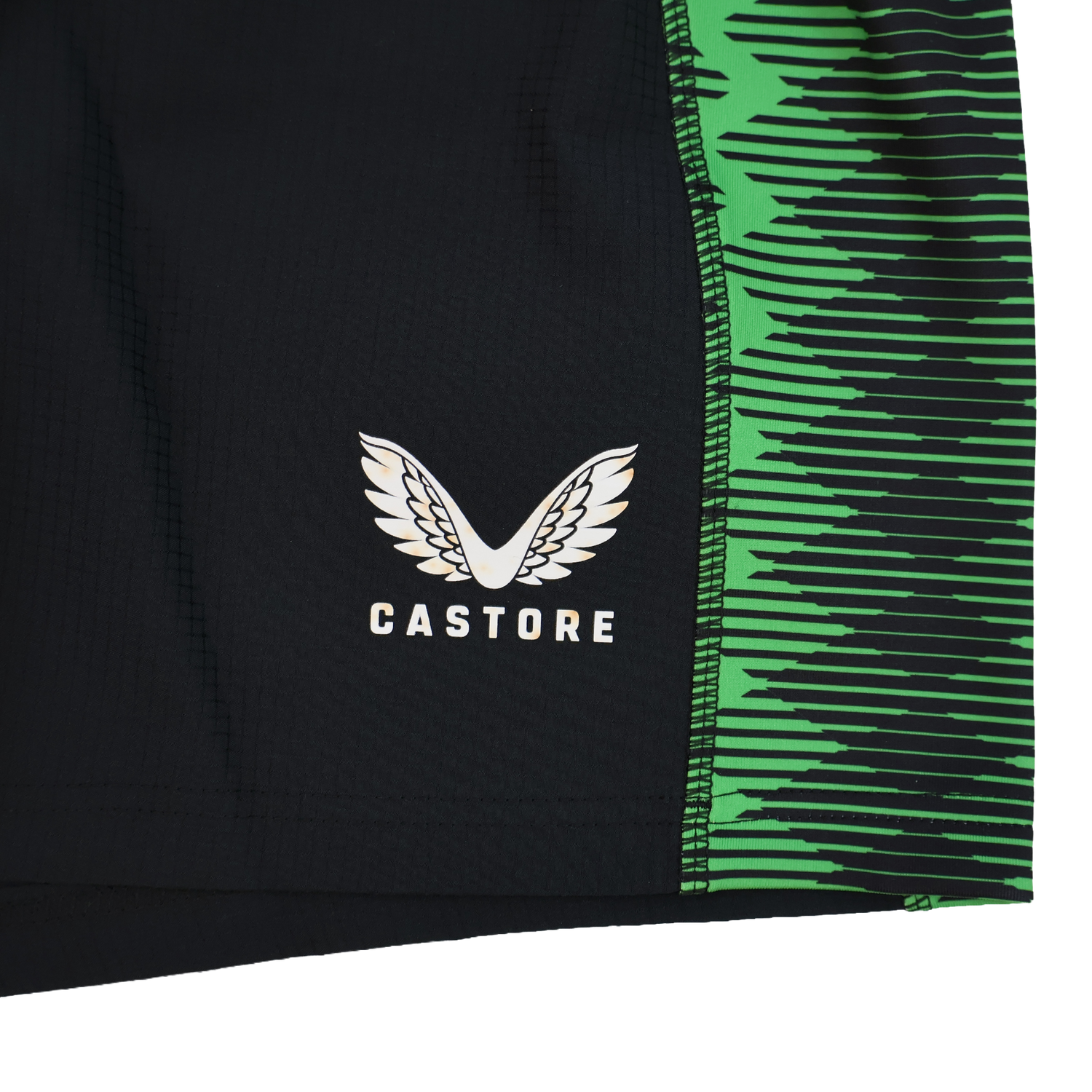 Close-up of the Harlequins 22/23 Home Shorts by Castore, featuring black fabric, a green zigzag side pattern, and the white Castore logo with stylized wings.