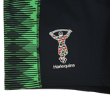 Close-up of Castore Harlequins 22/23 Home Shorts, featuring black fabric with green geometric patterns and the iconic multicolored harlequin rugby logo.