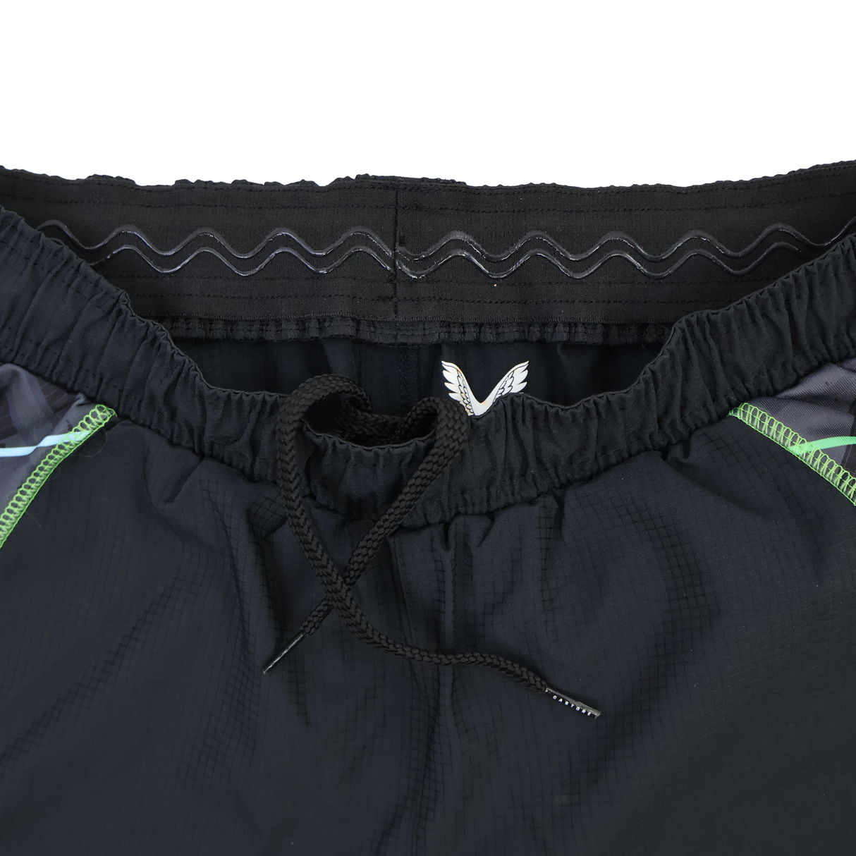 Close-up of the waistband on the Castore Harlequins 22/23 3rd Pro Short, showing a drawstring, elastic band with a wavy pattern, and green accent lines on the sides.