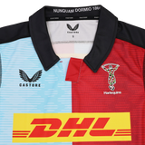 The Harlequins Replica Home Jersey 22/23 by Castore features blue and red panels, DHL sponsor logo, club crest, and a collar with "NUNQUAM DORMIO 1866"—a must-have for passionate fans.