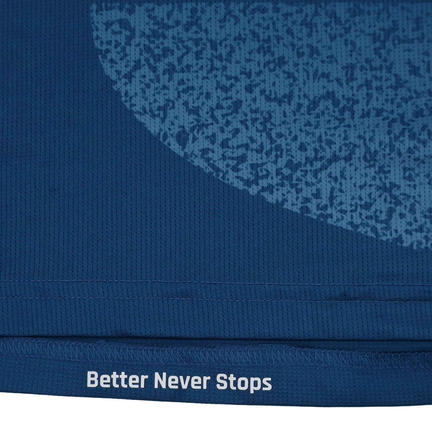 Close-up of the blue Scarlets Training Tee 22/23 by Castore, featuring a textured pattern and "Better Never Stops" printed in white along the bottom edge.