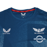 Close-up of the Scarlets Training Tee 22/23 by Castore, a blue performance shirt featuring the Castore logo, Scarlets rugby emblem, and Owens sponsor on the chest.