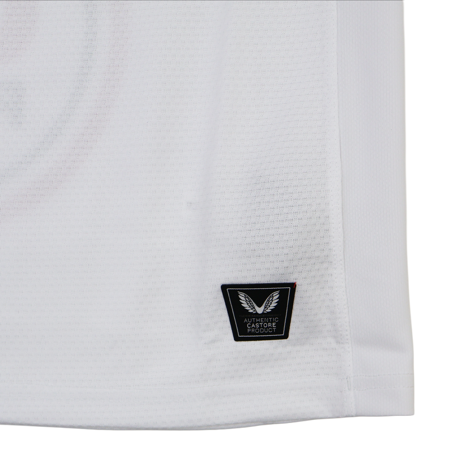Close-up of the lower part of the Ulster 25/26 Pro Home Jersey by Castore, showing a black "Authentic Fabrique" patch with a winged logo near the hem, designed in Castore's signature performance style.