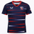 The USA Rugby 22/23 Pro Away Jersey by Castore features navy blue with red and white horizontal stripes, a red V-neck, Castore and USA Rugby logos, plus an American flag patch on the sleeve.