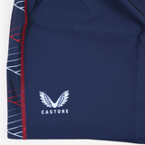 The USA Rugby 22/23 7's RWC Away Pro Short by Castore features navy blue fabric, a white Castore logo, red stitching, and white/red geometric side patterns—ideal for USA Rugby or 7's RWC fans.