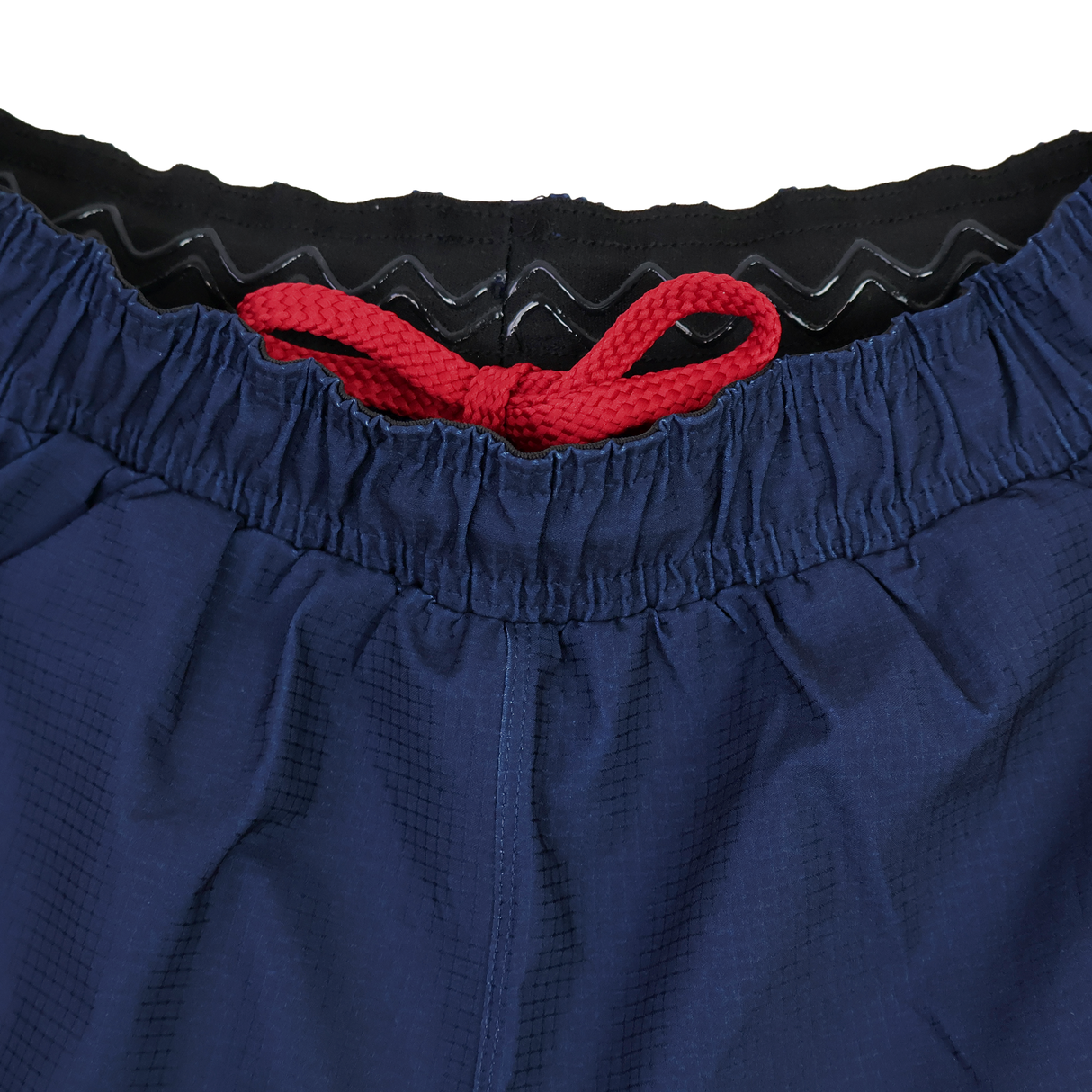 Close-up of the waistband on USA Rugby 22/23 7's RWC Away Pro Short by Castore, featuring a red drawstring and a black inner lining with wavy silicone grip.