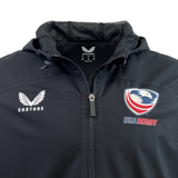 The USA Rugby Rain Jacket by Castore is a black zip-up featuring the USA Rugby emblem on the right and the Castore logo on the left, with lightweight mesh lining and water-resistant technology for comfort and protection.