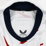 Close-up of the USA Rugby 23/24 Pro Away Jersey by Castore in white with a dark collar, showing the Castore brand label, care instructions, and "Made in China" tag inside the neckline—official team apparel.