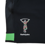Close-up of the Harlequins 23/24 Home Shorts by Castore, featuring a black design with the club’s colorful harlequin figure and "Harlequins" printed beneath.