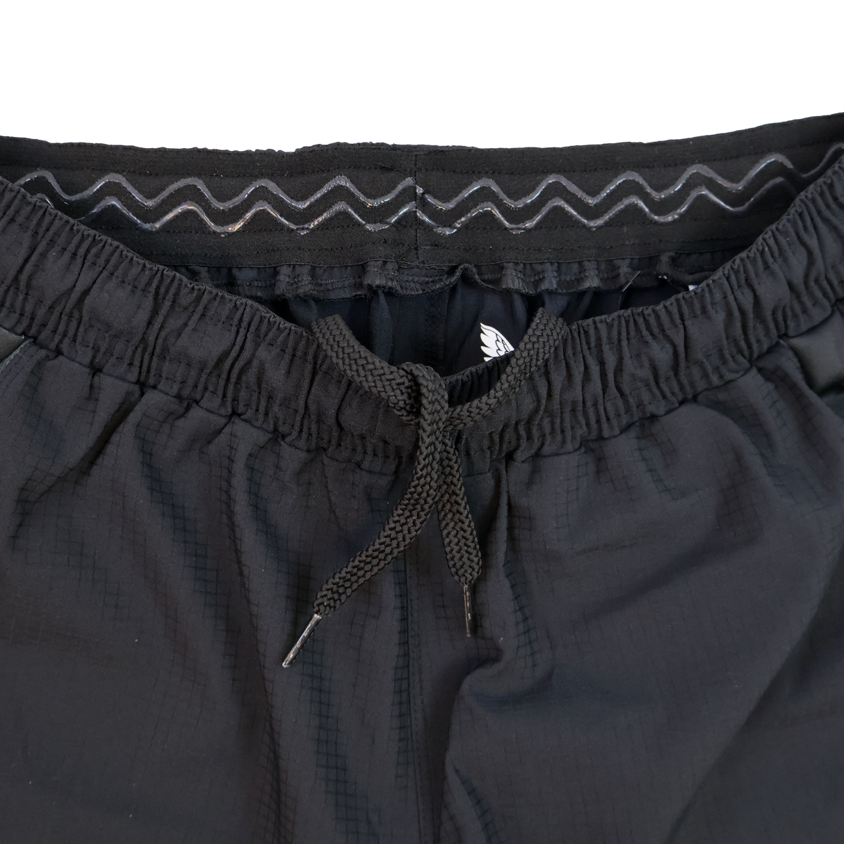 Close-up of Harlequins 23/24 Home Shorts by Castore, showcasing a black design with elastic waistband, drawstring, and zigzag stitching detail inspired by Harlequins' heritage.