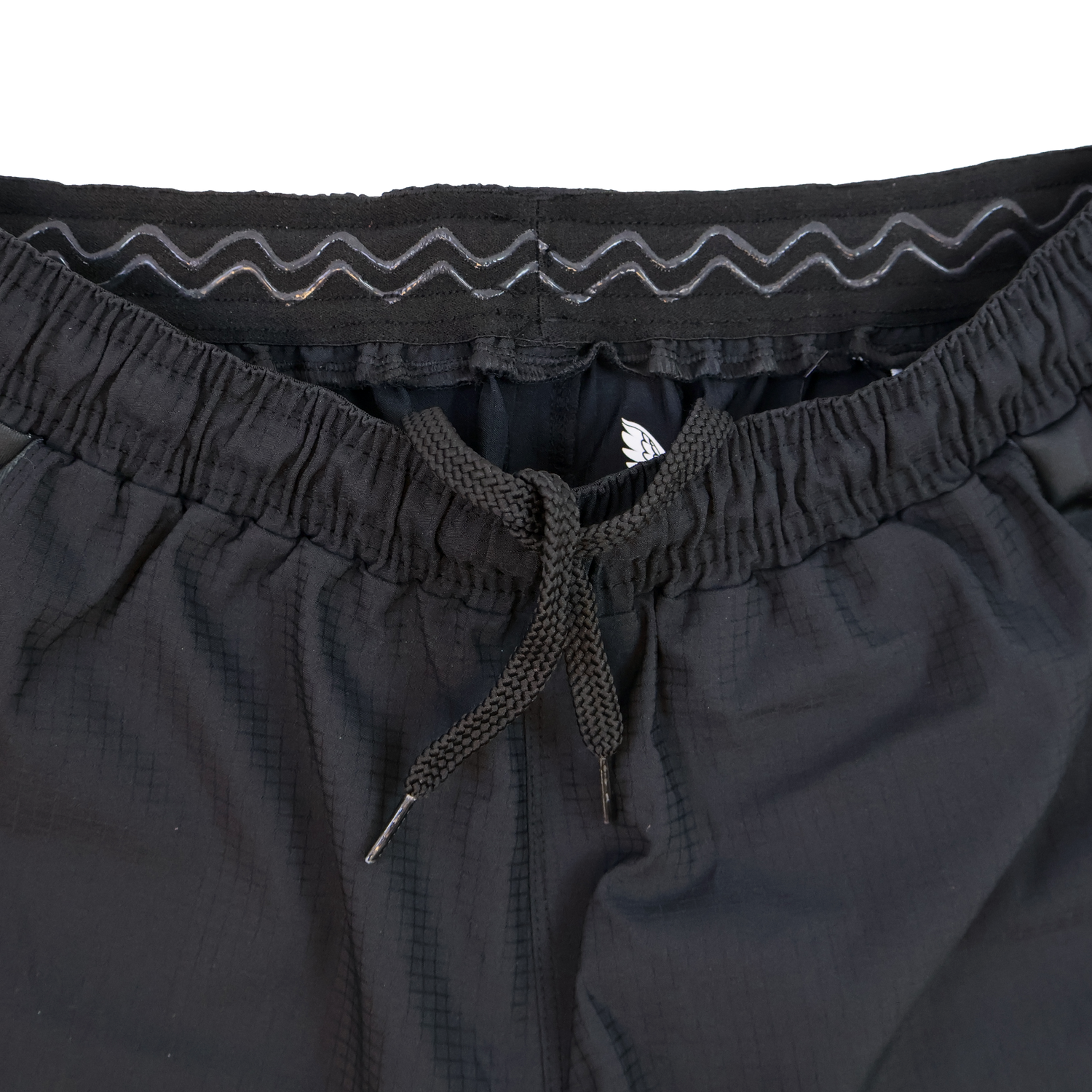 Close-up of Harlequins 23/24 Home Shorts by Castore, showcasing a black design with elastic waistband, drawstring, and zigzag stitching detail inspired by Harlequins' heritage.