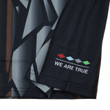 Close-up of the Harlequins 23/24 Replica Third Jersey by Castore, showing a dark geometric fabric with four colored diamonds and "WE ARE TRUE" near the hem—designed as a moisture-wicking football jersey.